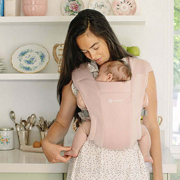 Mama mit Neugeborenem in pinker Embrace Neugeborenentrage