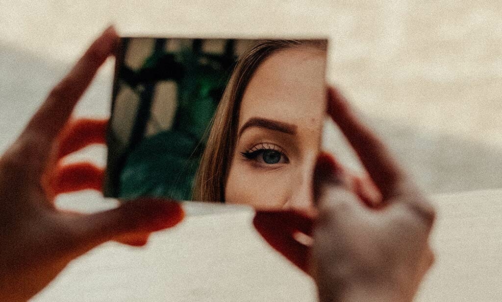 woman-in-makeup-looking-in-mirror-in-street