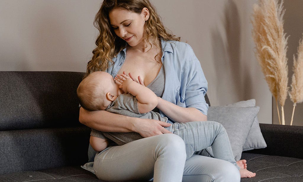 Stillen mit Brustimplantaten baby und Mama auf Sofa